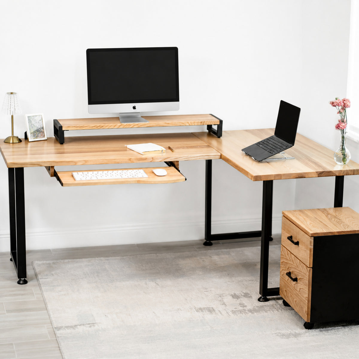 White oak L-shaped desk with computer setup in a room.