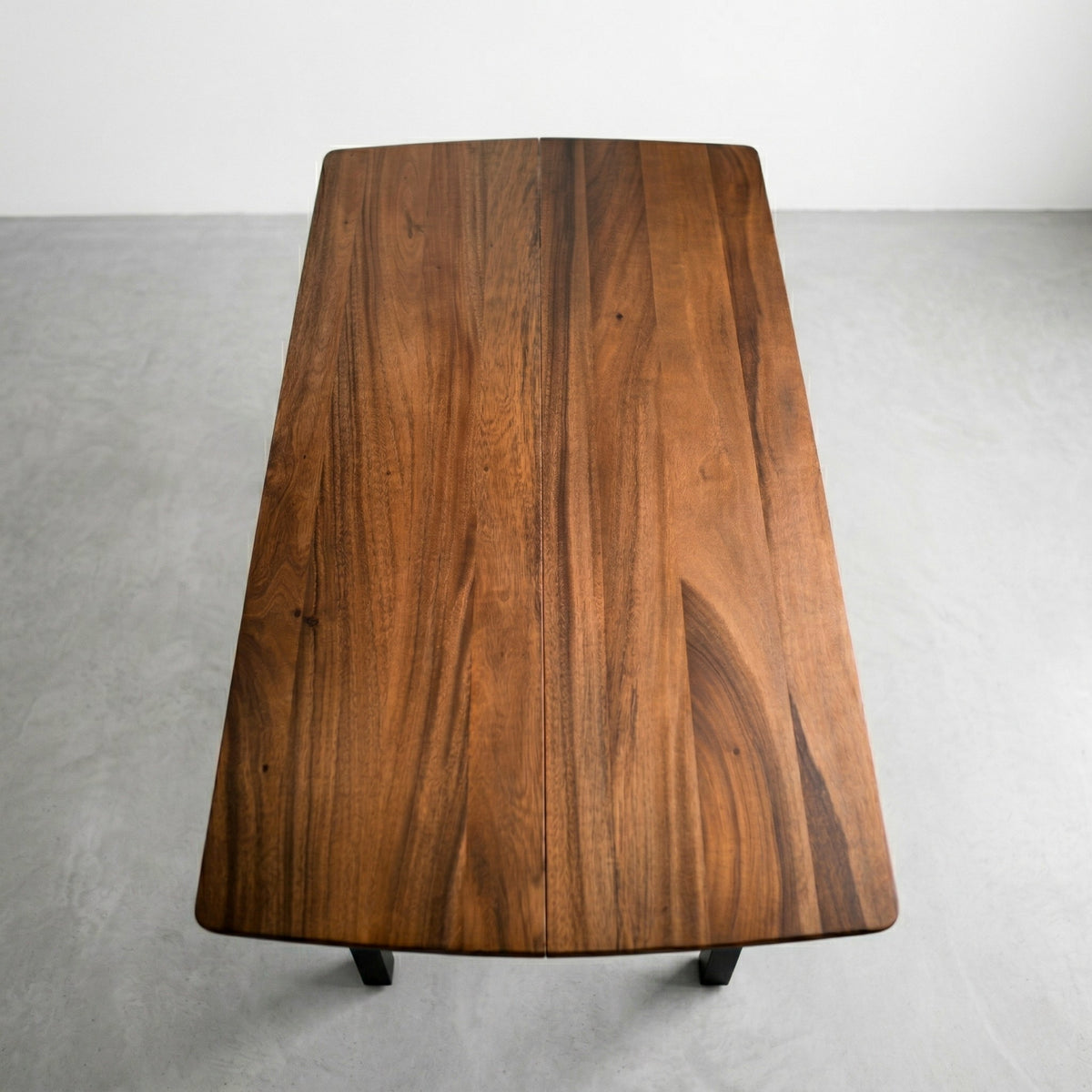 Solid walnut dining table with a natural finish on a gray background