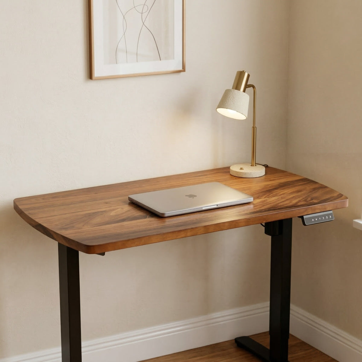 Narrow walnut standing desk with a laptop and lamp against a beige wall