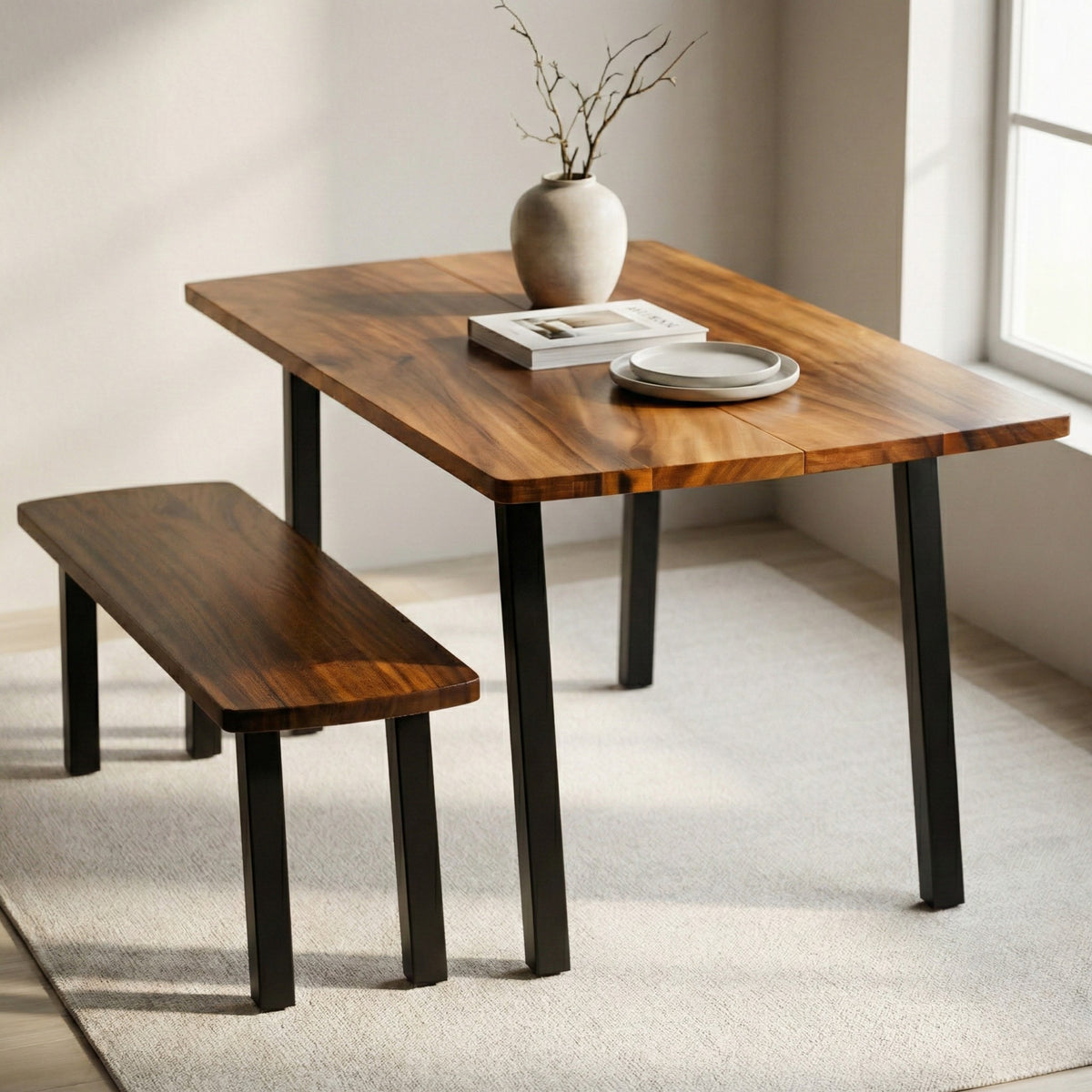 Solid walnut dining table with bench and black metal legs in a dining room with a window.