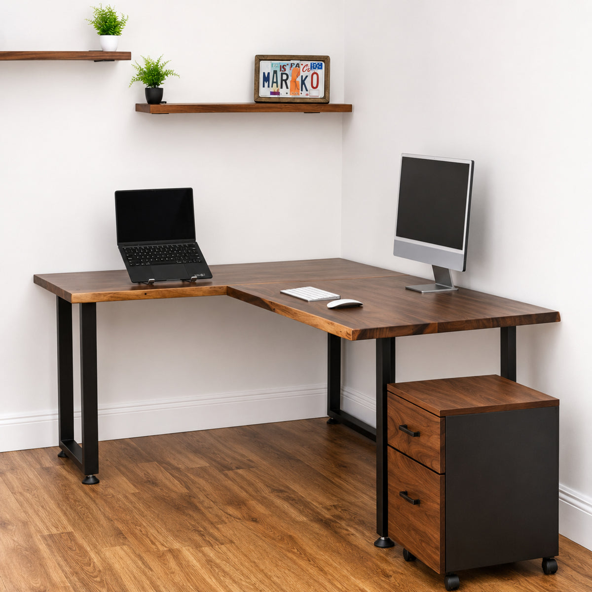 Walnut solid wood L-shaped desk with office equipment in a room with shelves and a white wall.