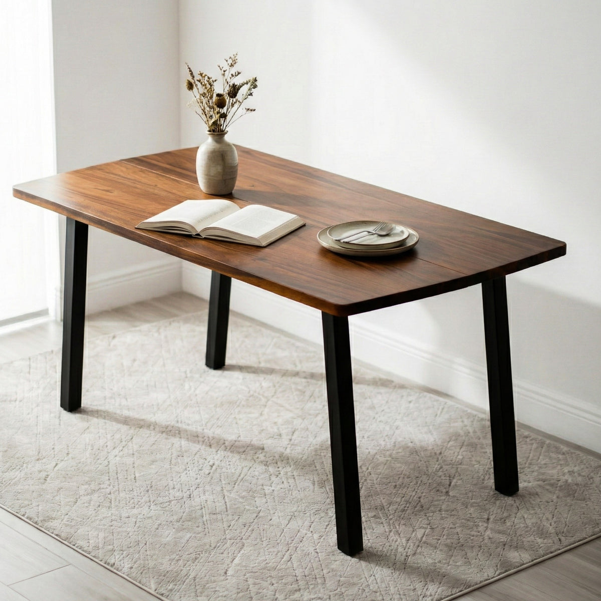 Solid walnut dining table with a vase, book, and plate on a light-colored rug.