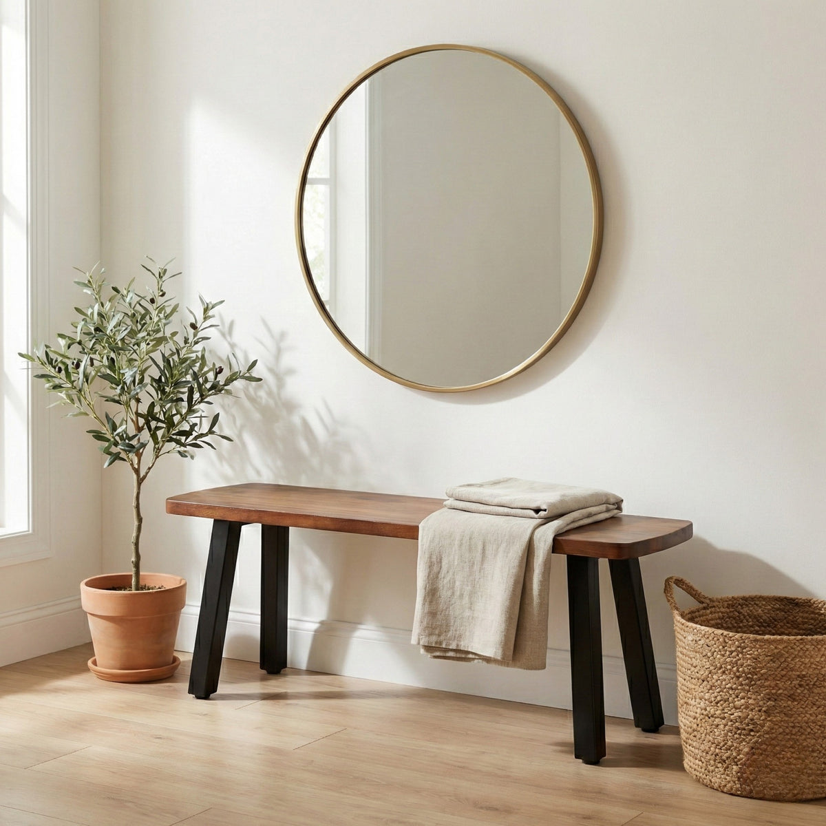 Wooden bench with a plant and basket in a room with a round mirror on the wall.