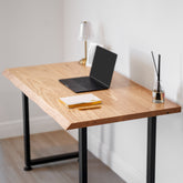 White oak computer desk with a laptop, notebook, and diffuser on a light background