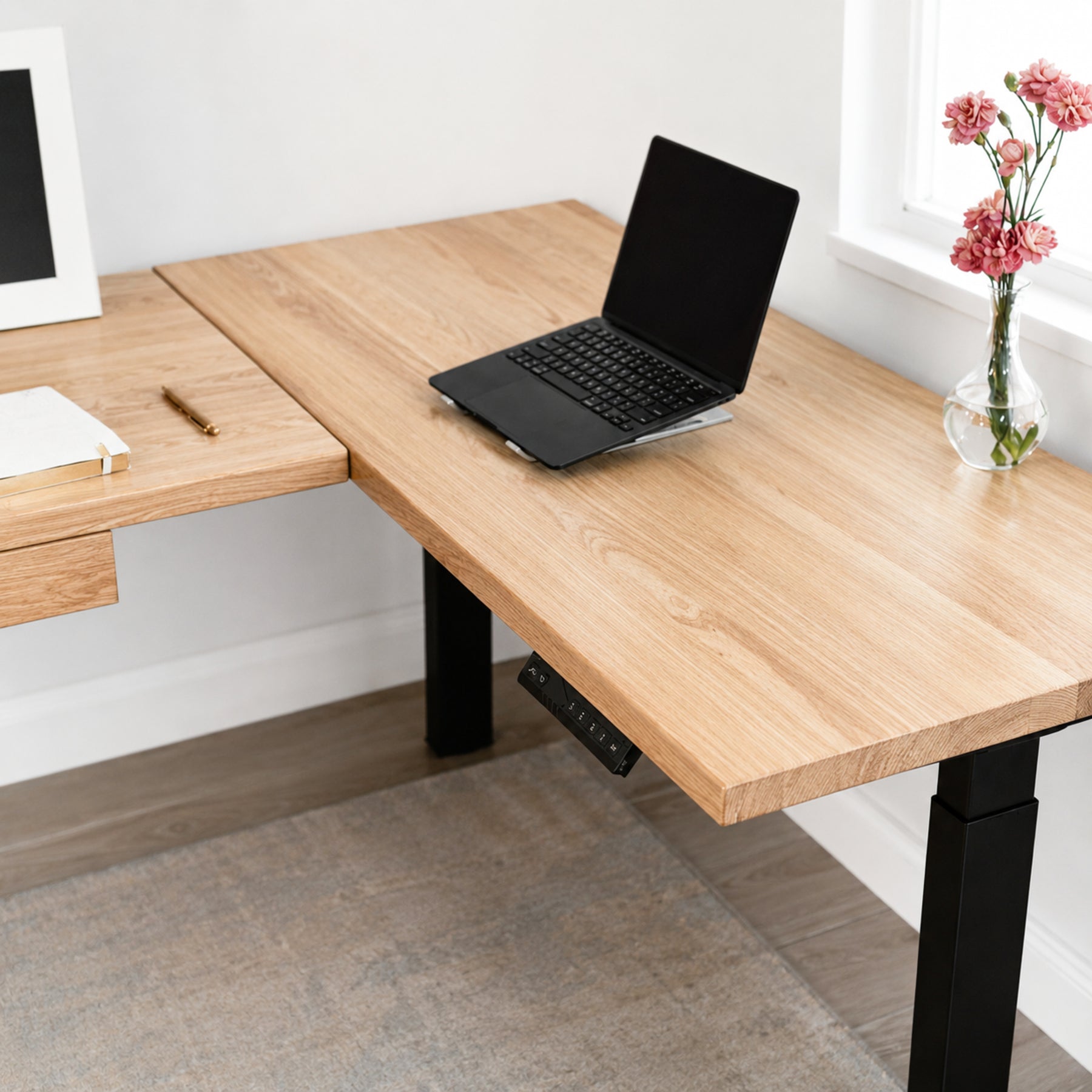 White oak L-shaped standing with a laptop, notebook, and vase of flowers in a home office setting.