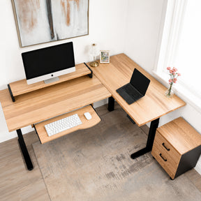 White oak L-shaped standing desk with computer setup in a home office.