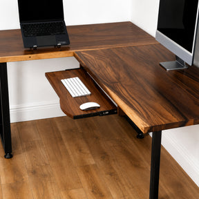 Walnut solid wood L-shaped desk with pull-out keyboard tray, laptop, and computer monitor.