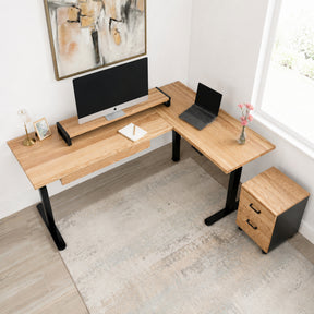 White oak L-shaped standing desk with computer setup in a home office.