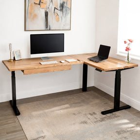 White oak L-shaped standing desk with computer setup in a home office.