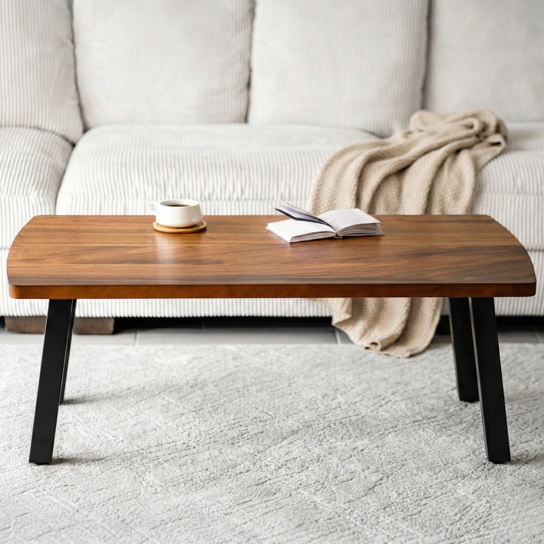 Walnut coffee table with a book and a cup in front of a white sofa