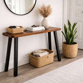 Solid wood console table with black legs in a room with a mirror, books, and decorative items.