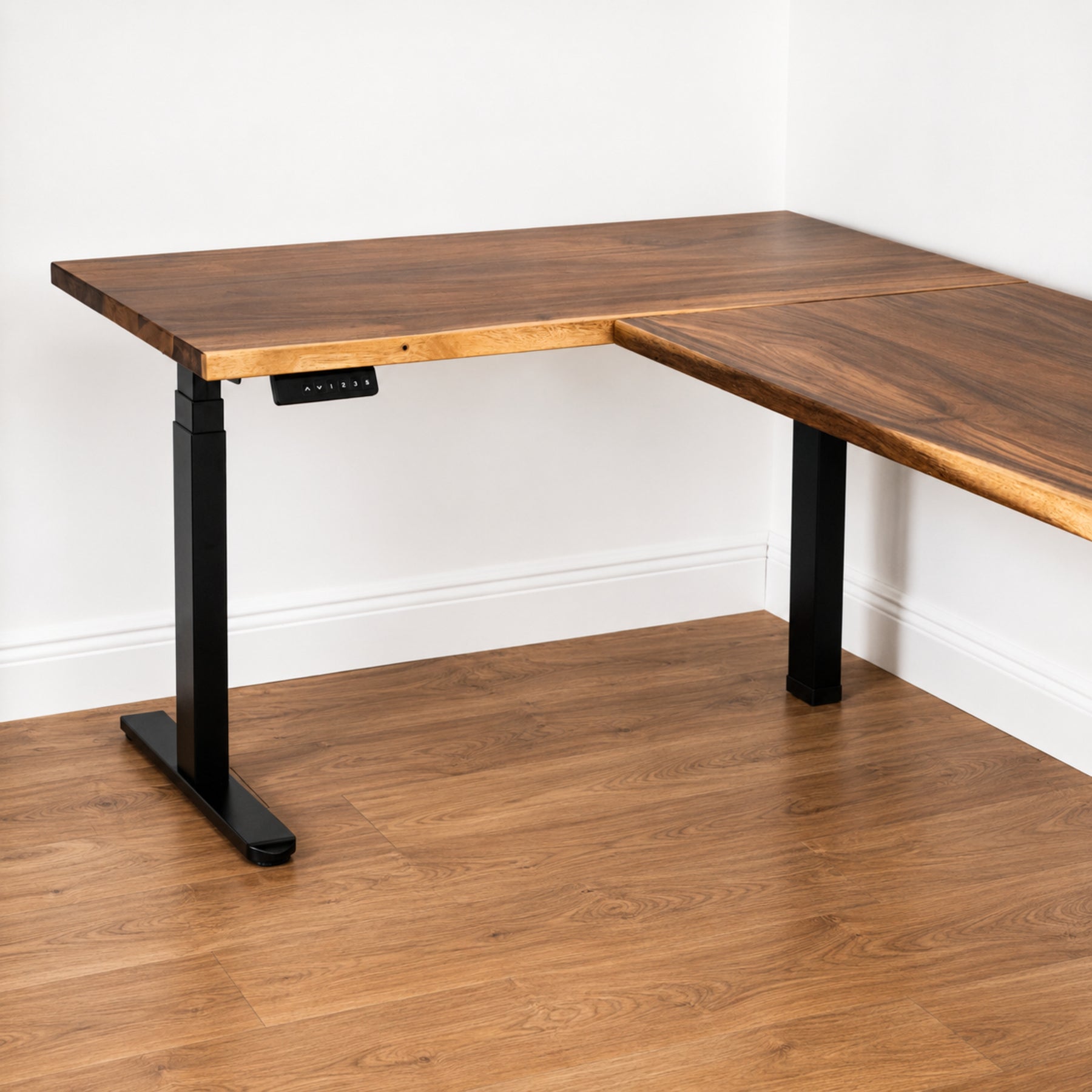 Walnut L-shaped standing desk with black metal legs on a wooden floor.