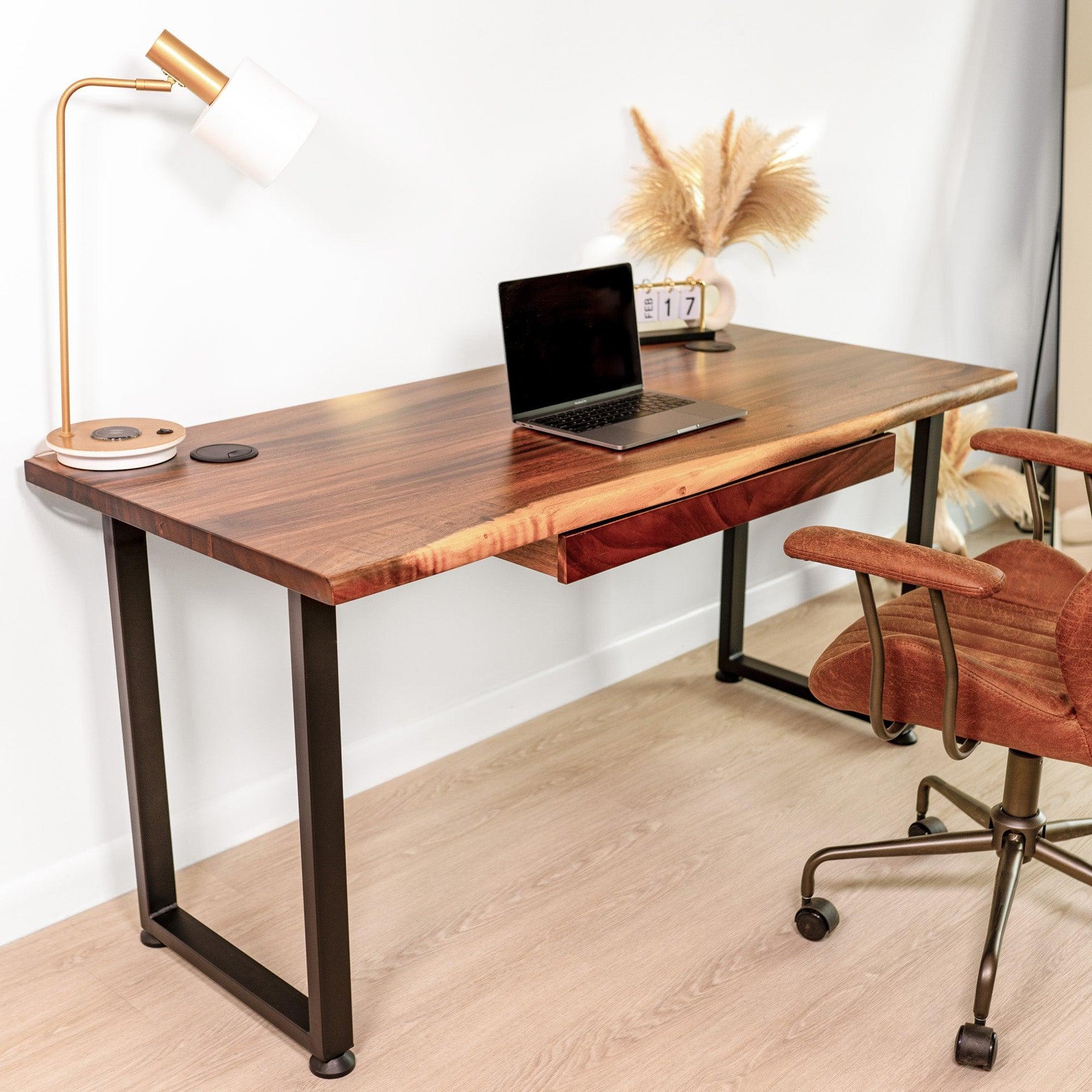 Side view of a walnut solid wood computer desk with drawer, paired with a brown office chair, laptop, and modern desk lamp, creating a sophisticated and stylish home office setup.