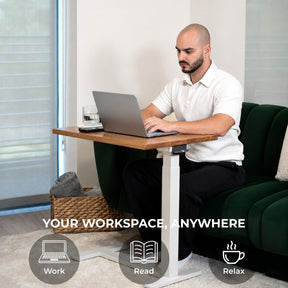 Person using an adjustable white oak laptop desk beside a sofa as a compact mobile workspace