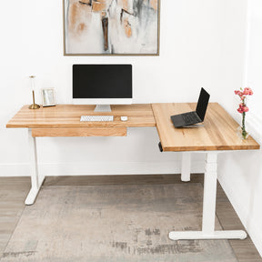 White oak L-shaped standing desk with computer setup in a modern office.