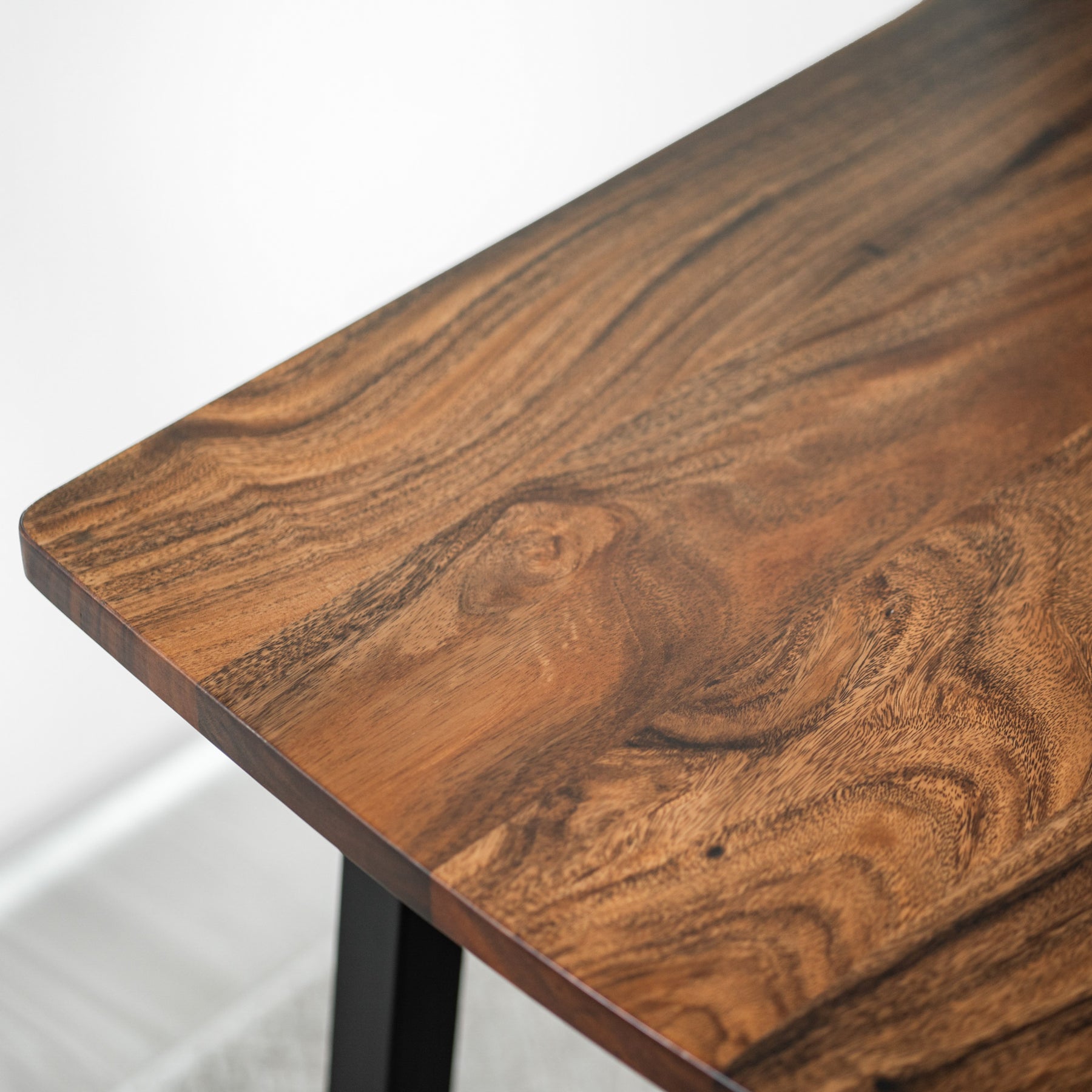 Close-up of a walnut table with a wavy grain pattern on a white background