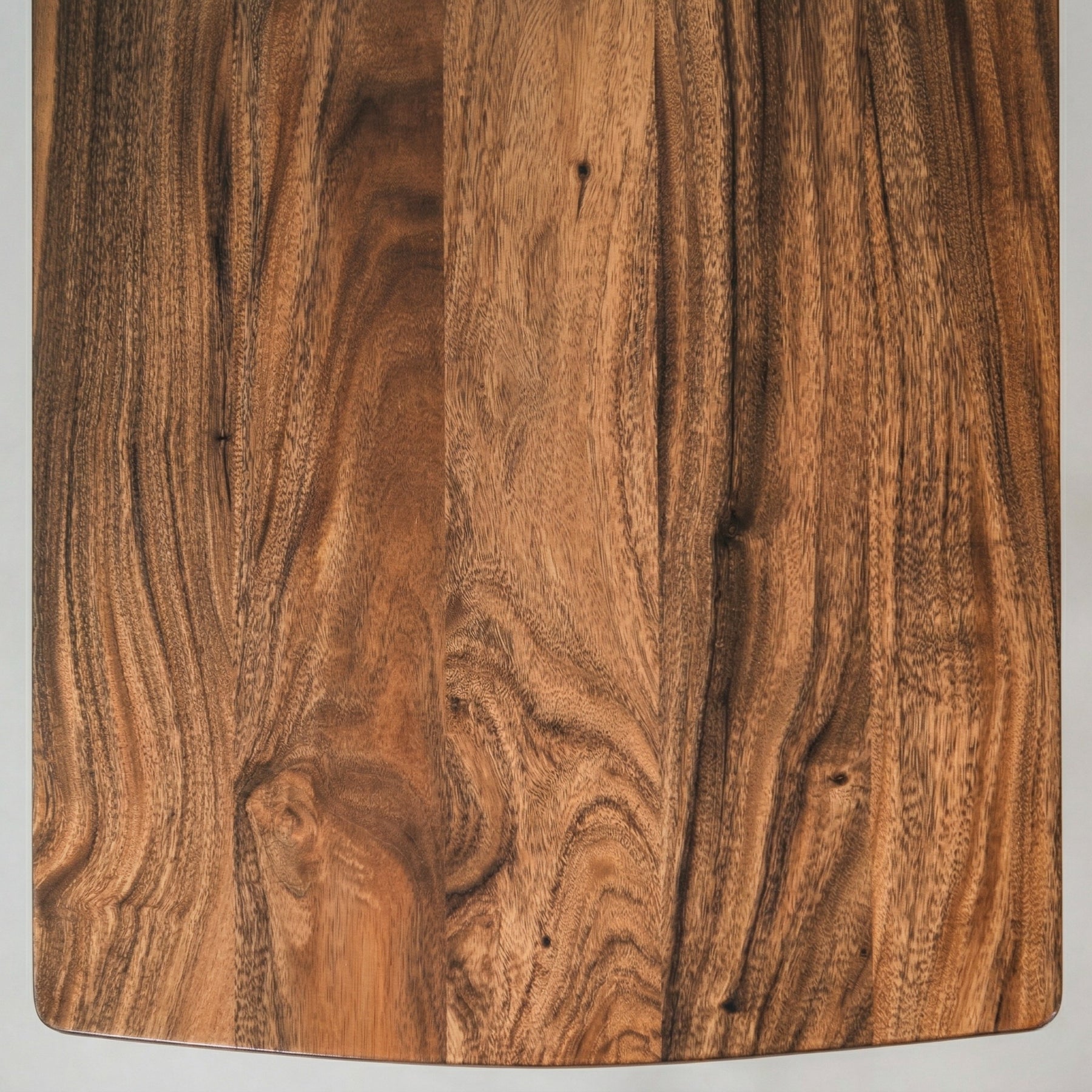 Close-up of a walnut dining table top with a natural grain pattern.