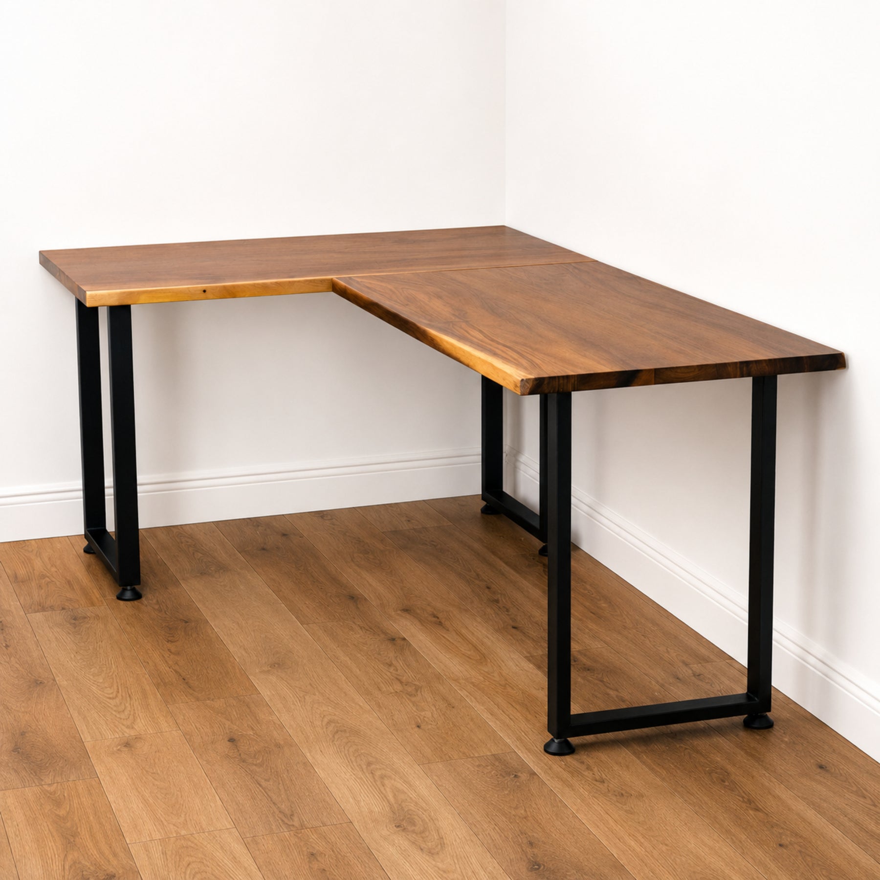 Walnut solid wood L-shaped desk with black metal legs on a wooden floor.