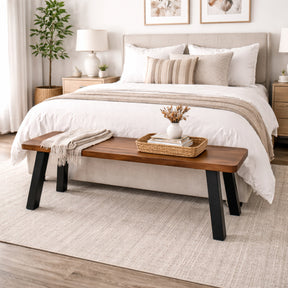 Wood bench in front of a bed with decorative items in a bedroom setting