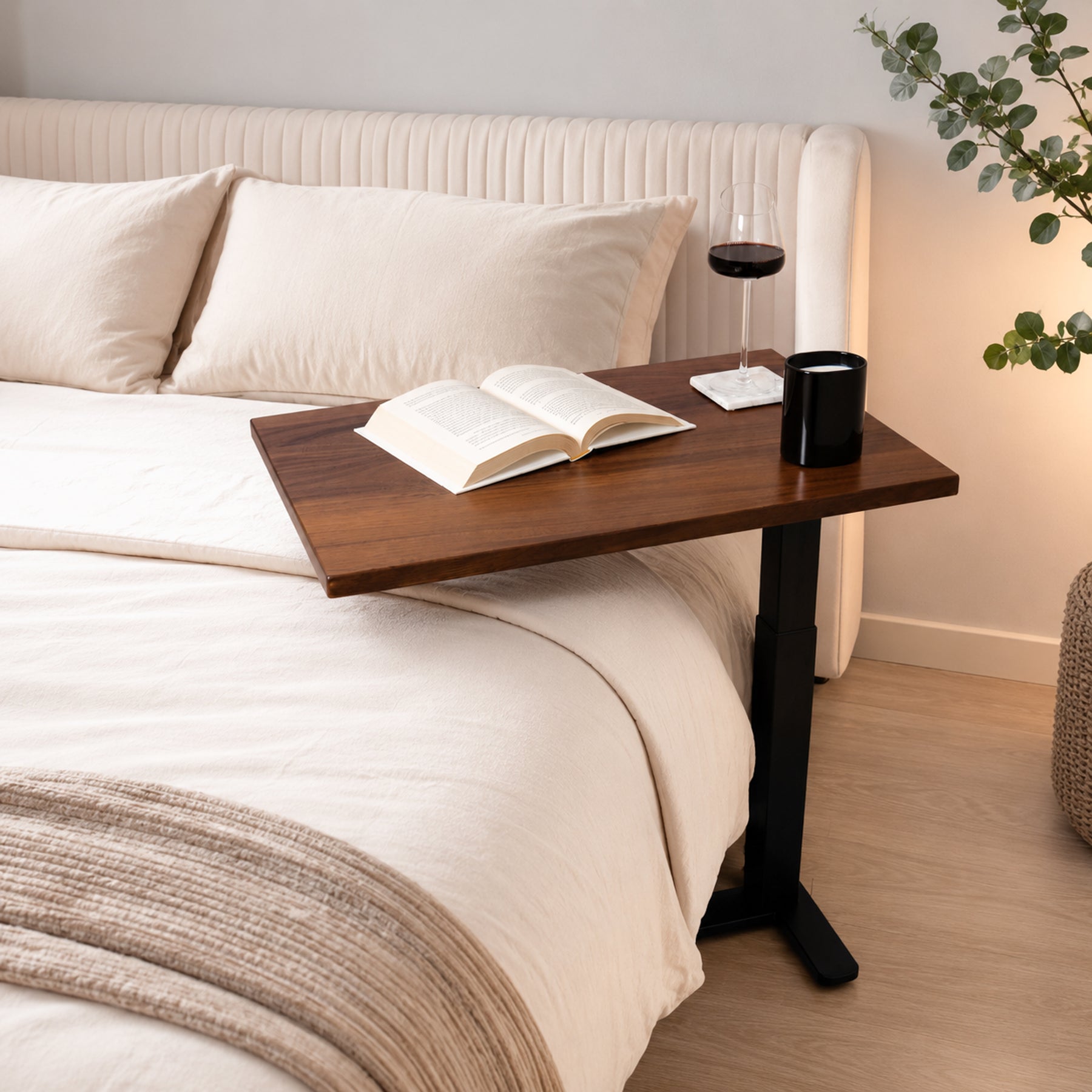 Solid walnut rolling laptop desk positioned over a bed for reading, drinks, and relaxed bedside use