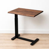 Solid walnut rolling laptop desk with live-edge top, black pneumatic frame, and low-profile wheeled base