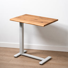 Solid white oak mobile laptop desk with natural live-edge top, white pneumatic frame, and rolling base