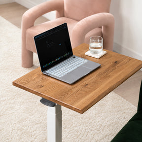 Solid white oak mobile laptop desk with natural live-edge top, white pneumatic frame, and rolling base