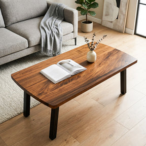 Walnut coffee table with an open book and a vase in a living room setting.