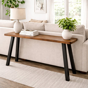 Walnut sofa table with black legs in front of a beige sofa in a living room.