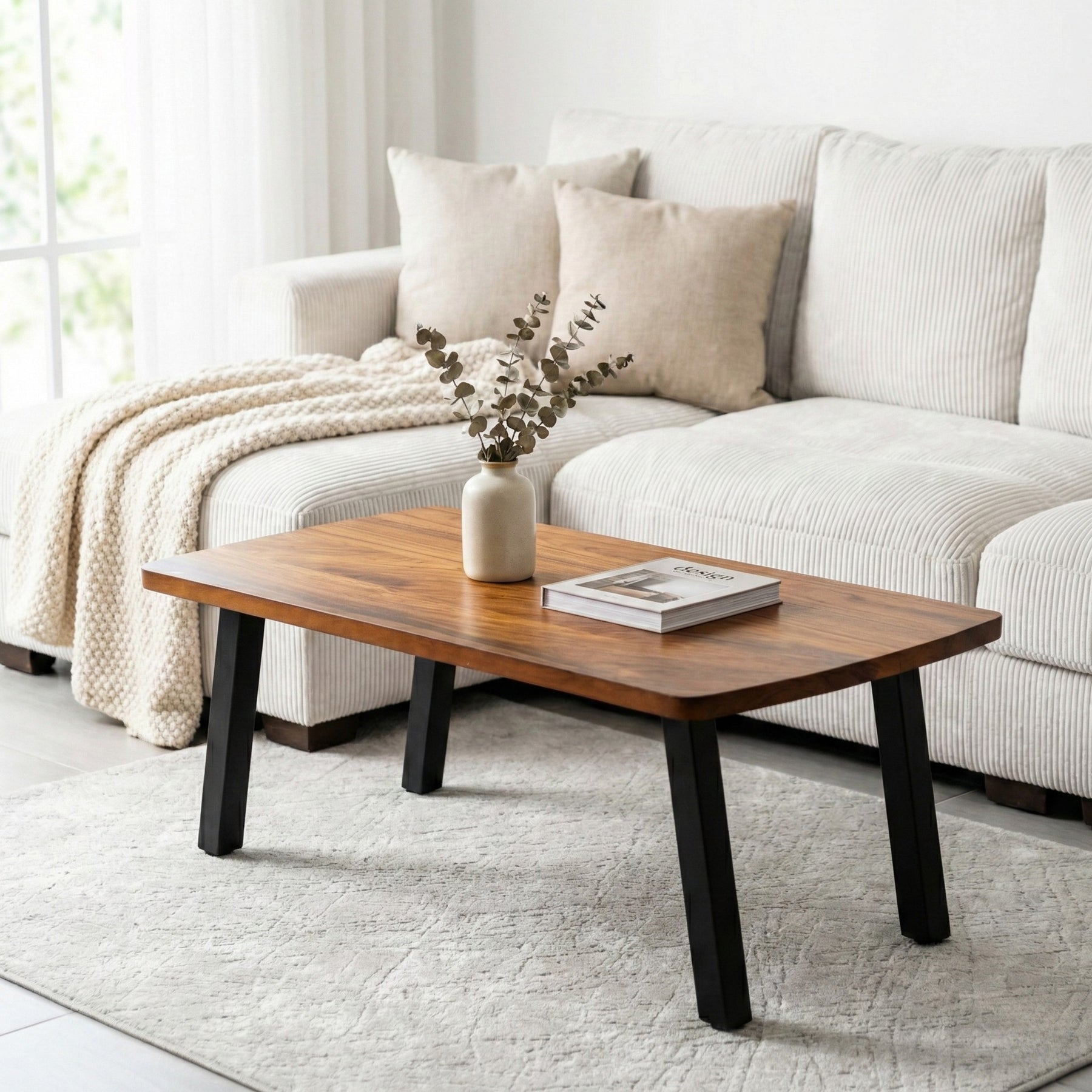 Walnut coffee table in front of a white sofa with decorative items on a light gray rug.