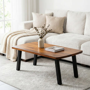 Walnut coffee table in front of a white sofa with decorative items on a light gray rug.