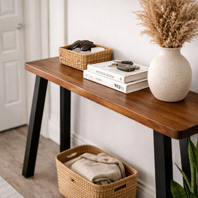 Wood console table with books, a basket, and a vase in a room setting.