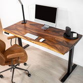 Side view of solid wood standing desk with black sit stand desk legs, featuring home office setup