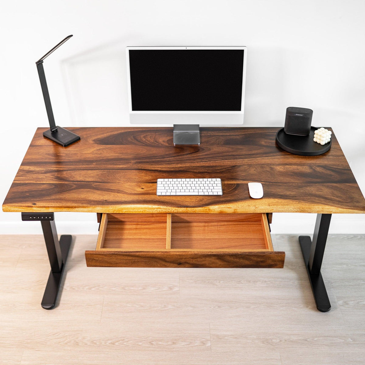 Top view of walnut standing desk with black adjustable height legs and integrated drawer storage