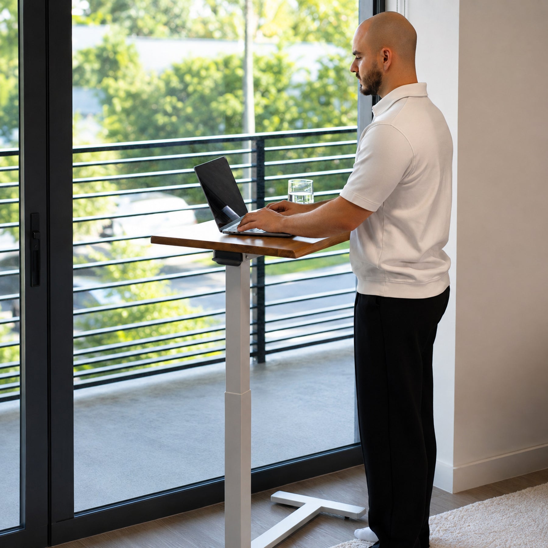 Person working while standing at a height-adjustable white oak mobile laptop desk