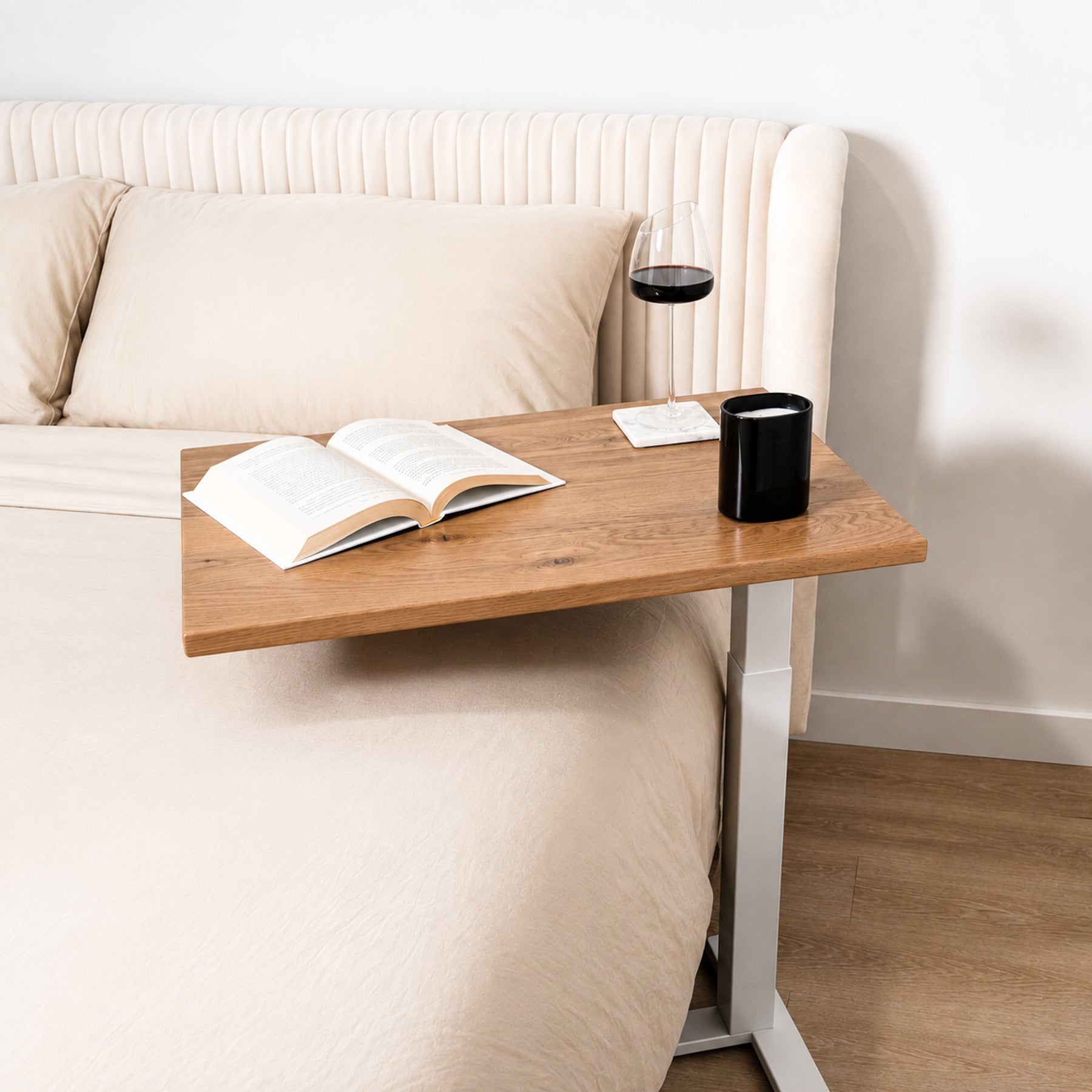Solid white oak rolling laptop desk positioned over a bed for reading, drinks, and relaxed bedside use