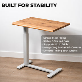 White oak pneumatic standing desk with white steel C-shaped frame, 60-pound capacity, and rolling wheels