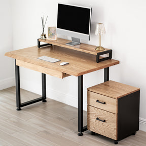 White oak computer desk with a drawer, black metal legs, and a matching storage unit against a white wall.