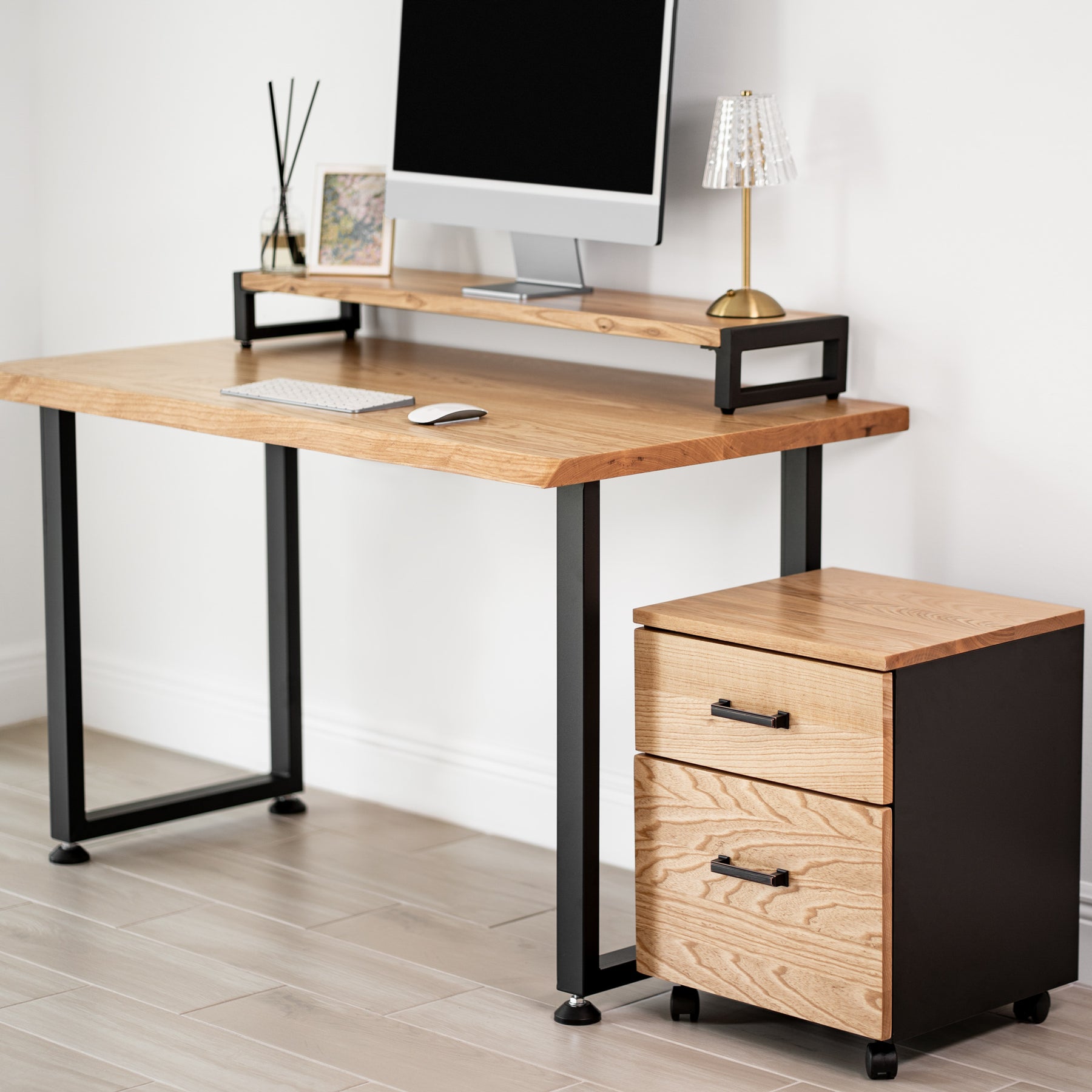 White oak computer desk with black metal legs and a matching file cabinet against a white wall.