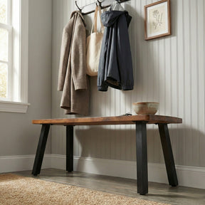 Wooden bench in a room with coats and a bag hanging on hooks above it.